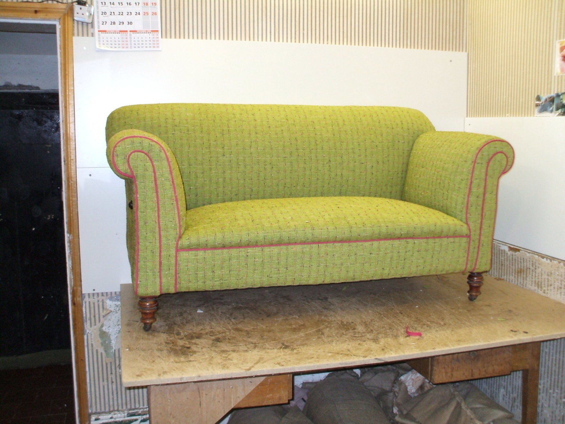 Green settee in the workshop with pattern books and fabric samples behind it