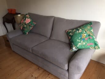 Grey three-seat sofa in a home room styled with green patterned cushions