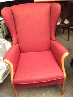 Red wingback chair with pale wooden arms in the workshop