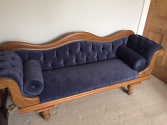 Dark blue buttoned chaise longue with wooden trim and bolsters