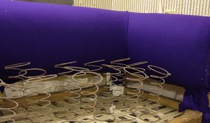 Underside of a chair frame exposed during structural spring repair work